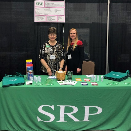 Two women smiling in front of SRP table dropcloth
