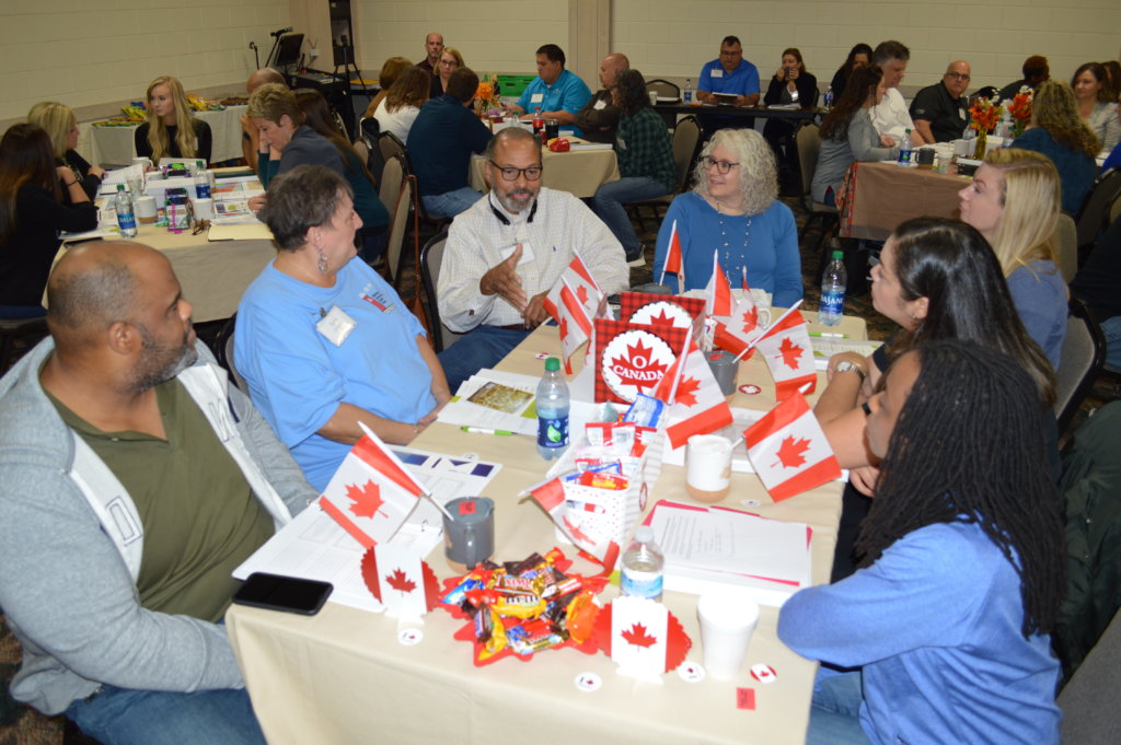 Group of people sitting around table talking with Canadian flags in front of them