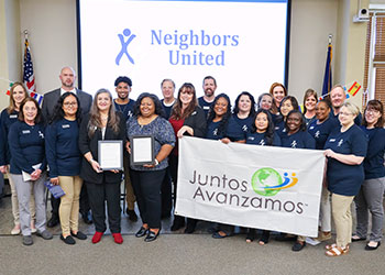 Group of Neighbors United FCU employees and honorees holding Juntos Avanzamos banner